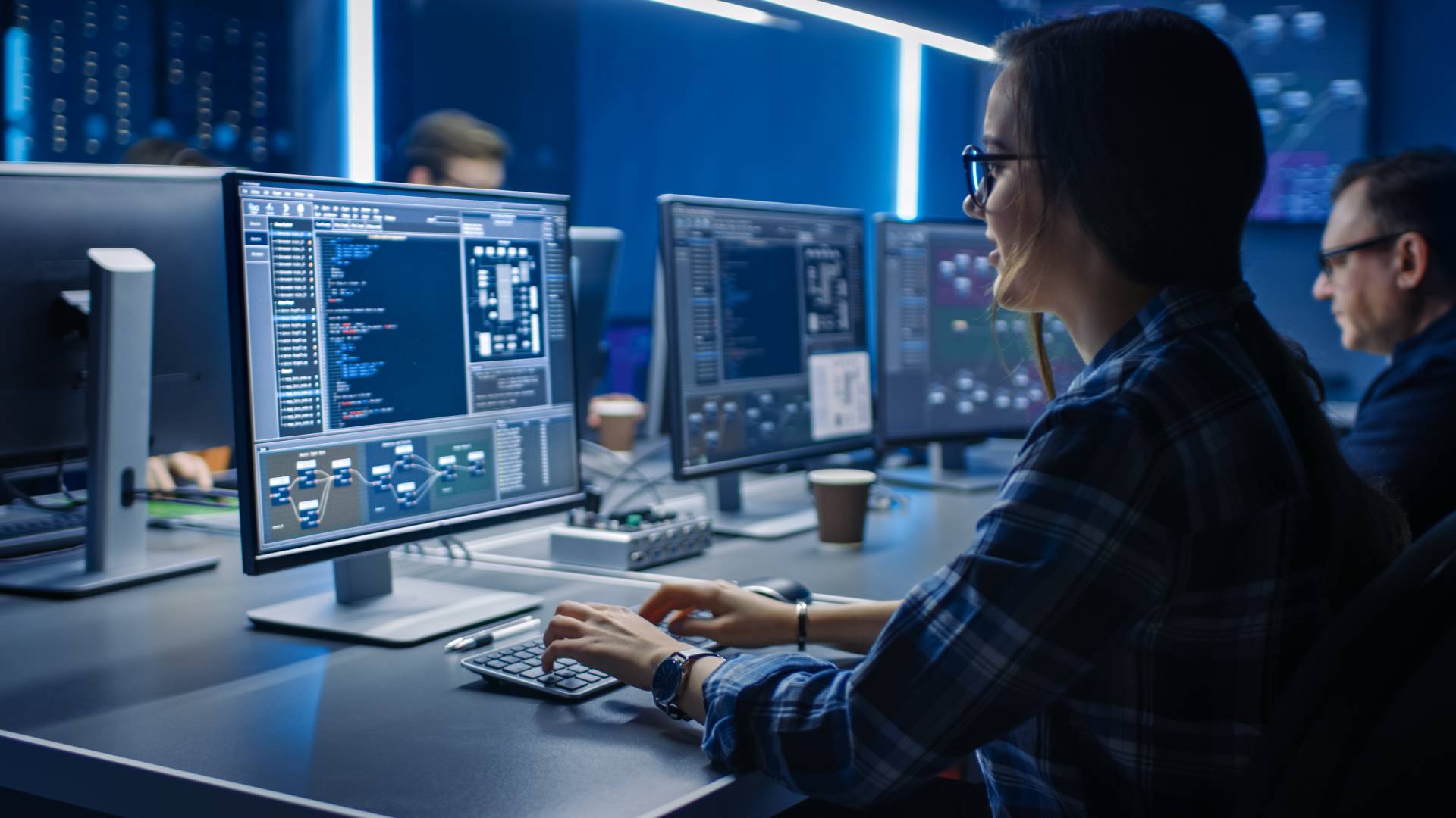 Photograph of a woman at a desk programming on a computer