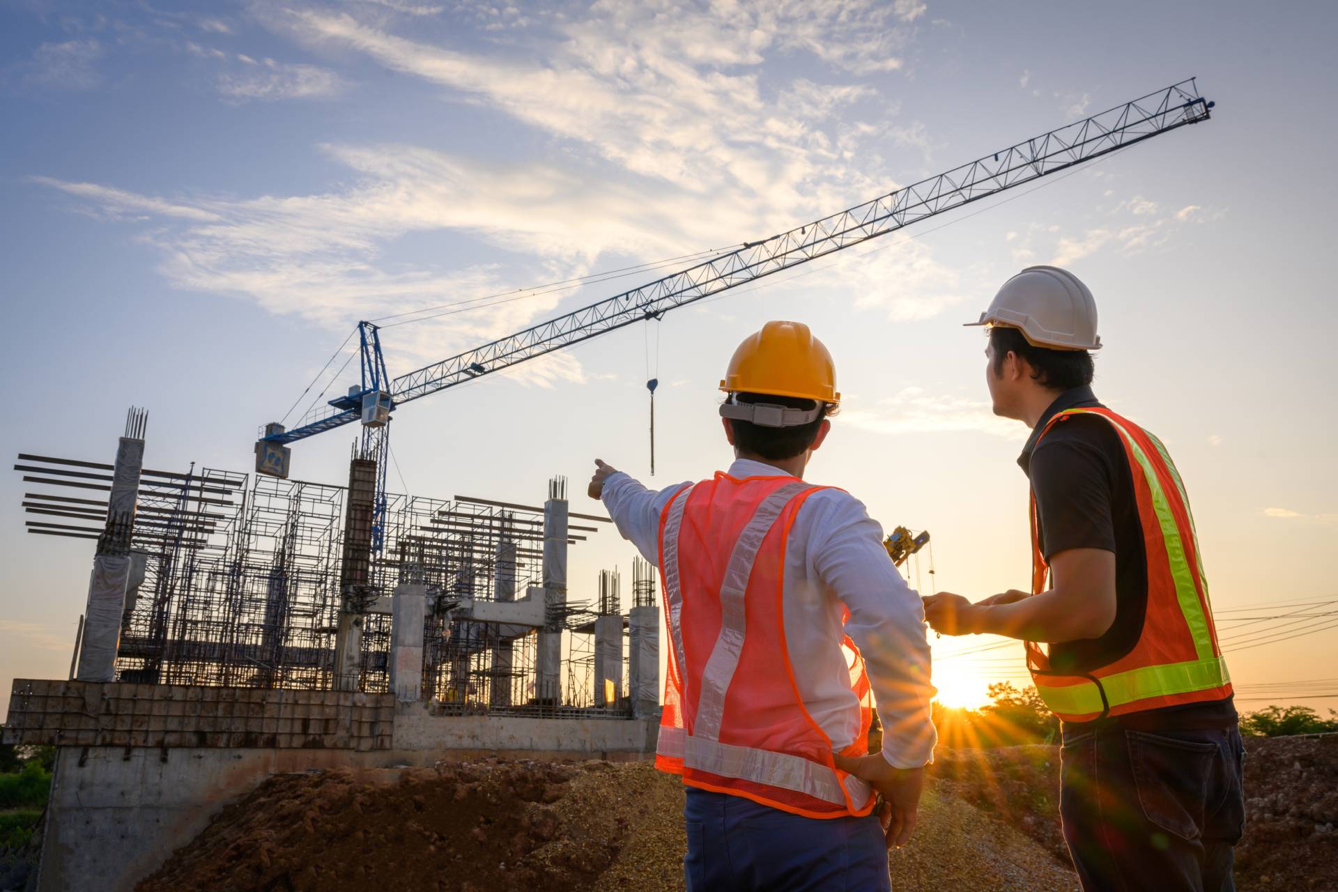 Photograph of two men in high-vis and safety helmets looking at a construction site