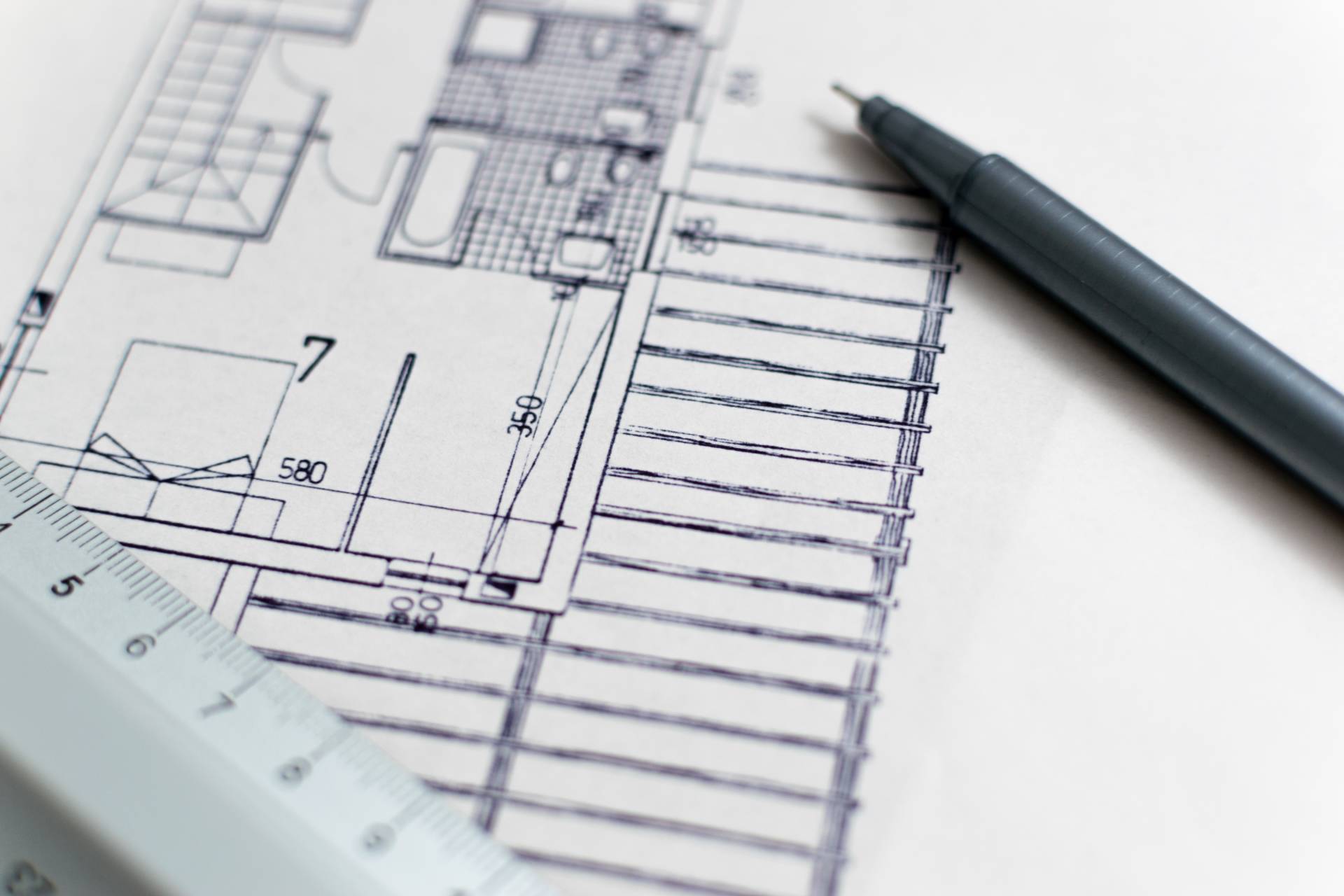 Photograph of blueprints with a pen and ruler
