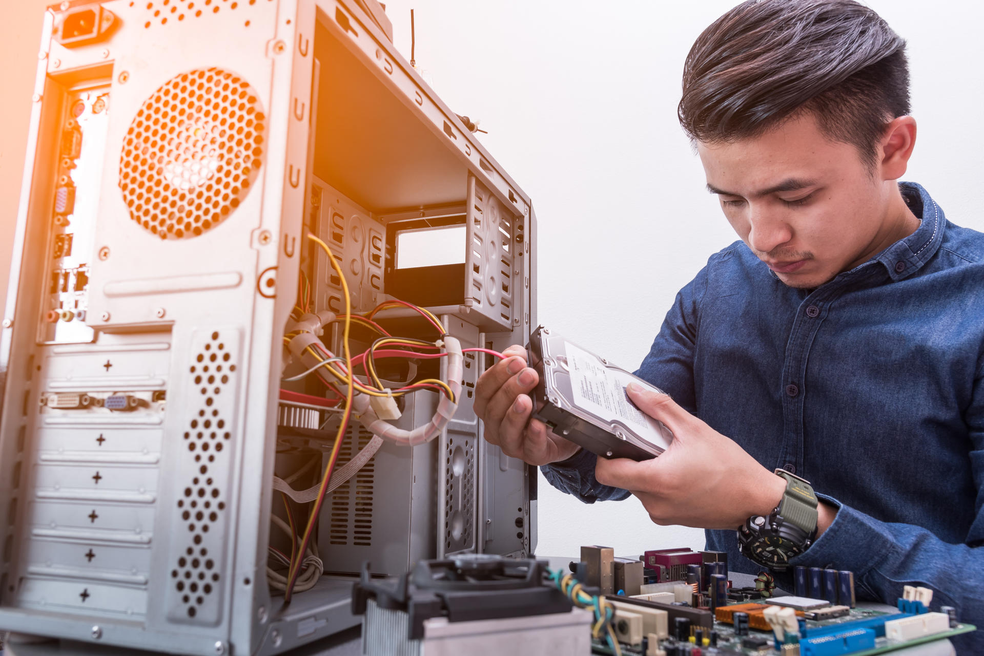 Photograph of a man fixing/taking apart a computer tower