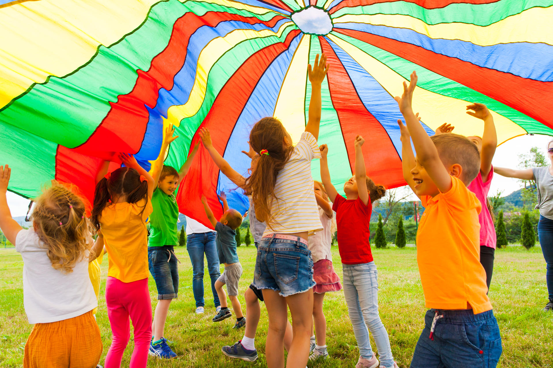 Photograph of a group of children playing under a colourful parachute