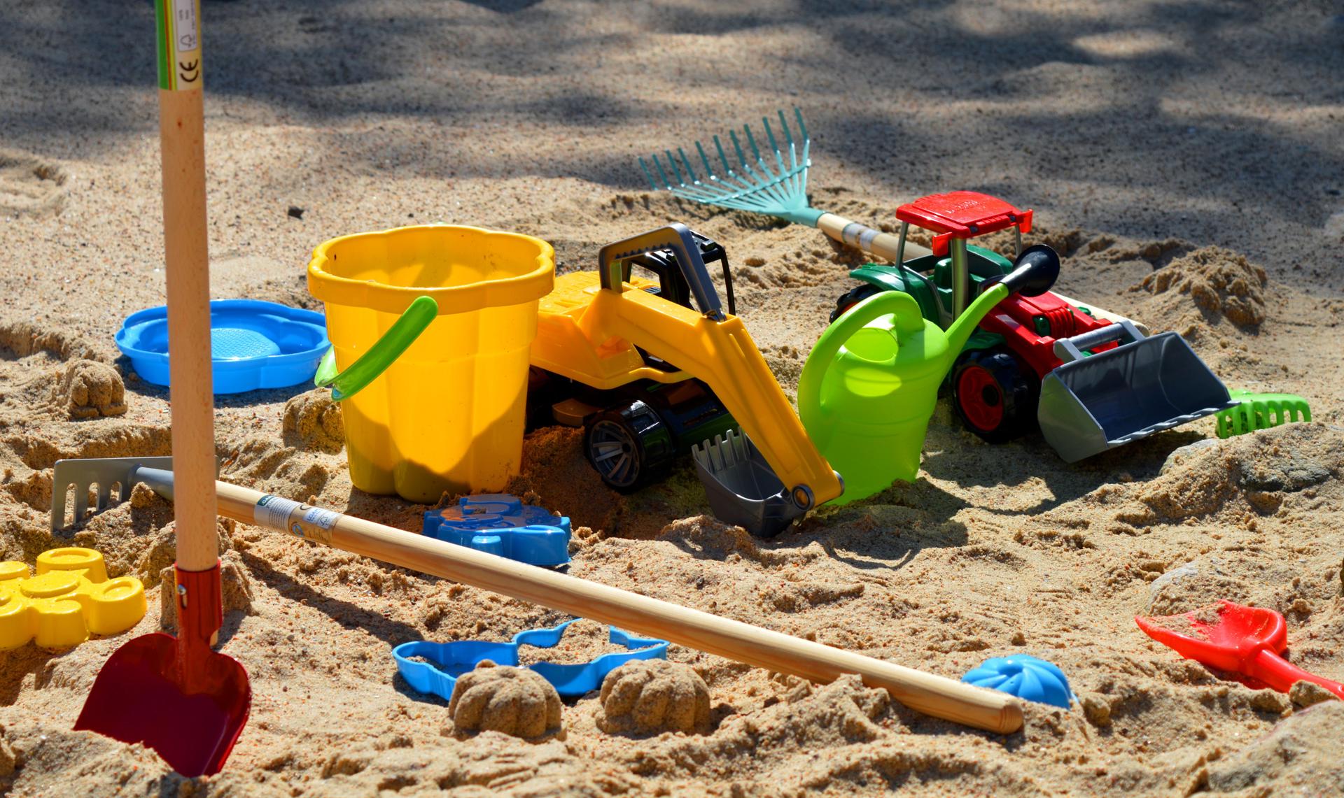 Photograph of a children's sand pit with play equipment such as buckets, spades and tractors