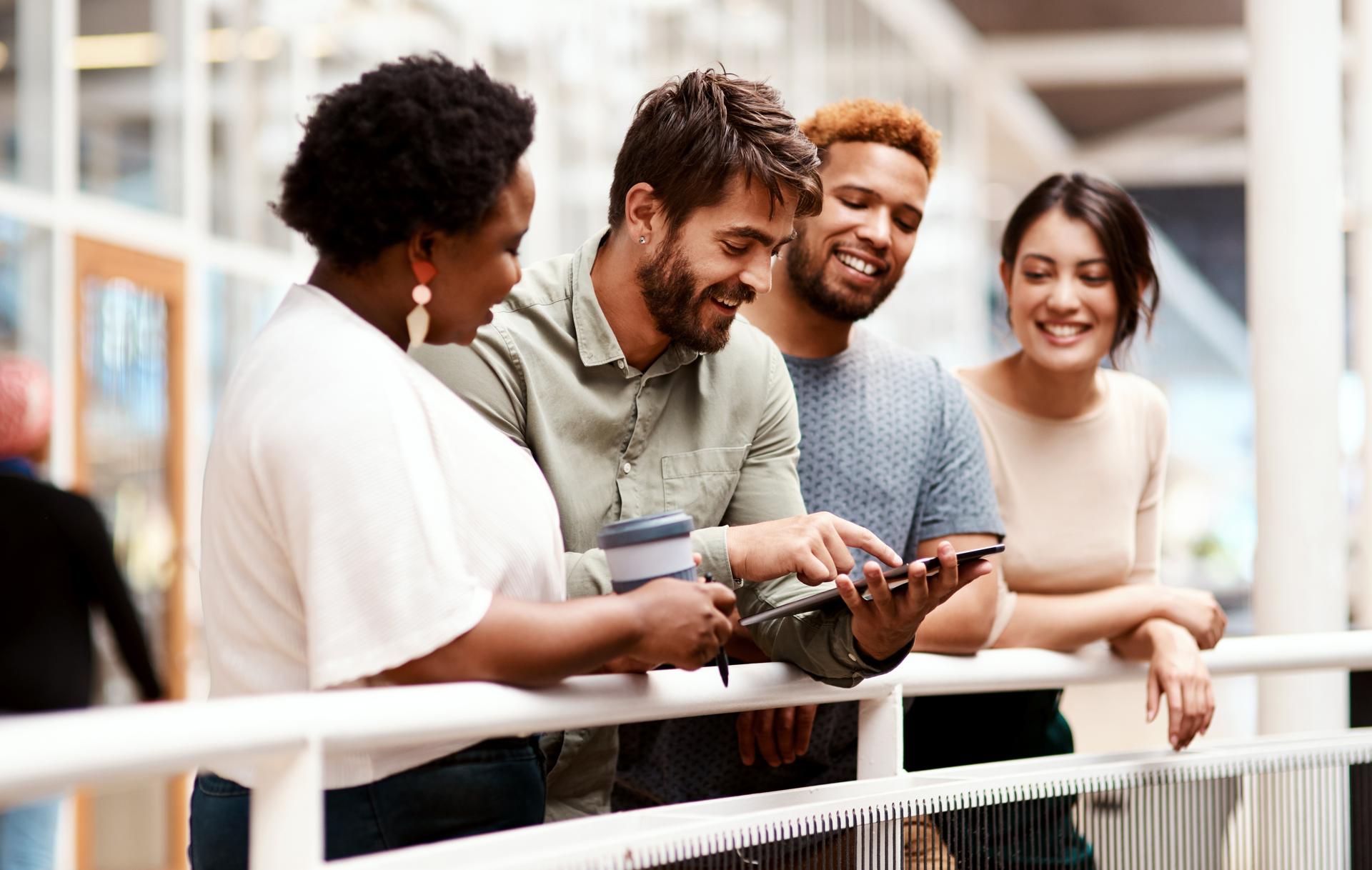 Photograph of four people looking at an iPad screen together