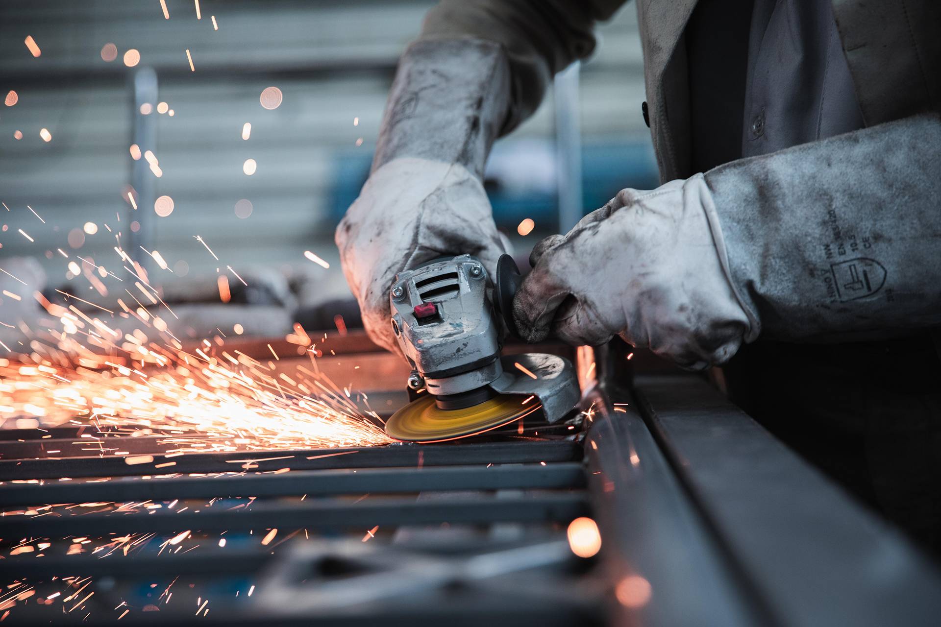 Photograph of a worker using tools on metal, with sparks flying from the tool