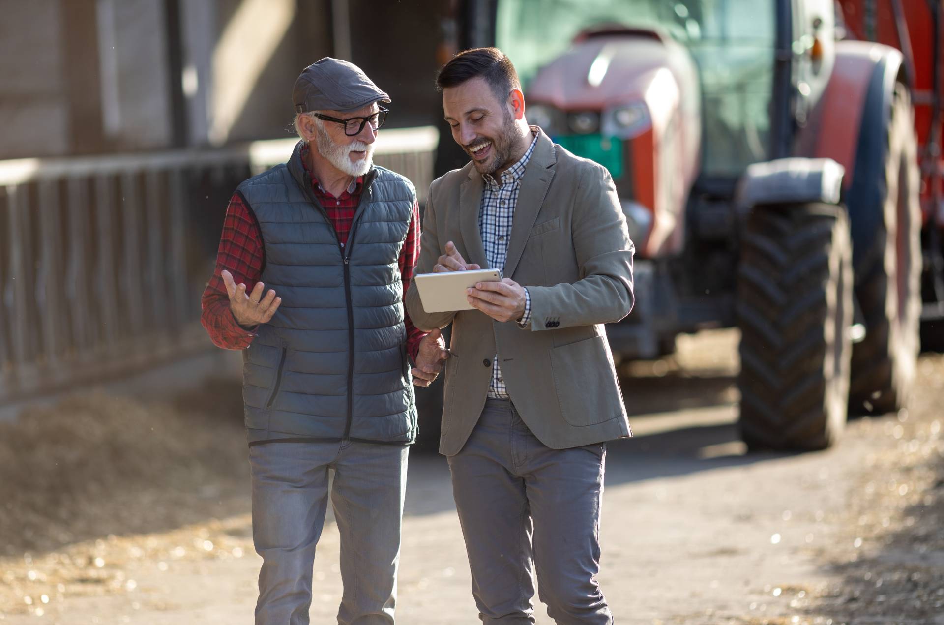 Photograph of a farmer talking to a businessman, both looking at a tablet