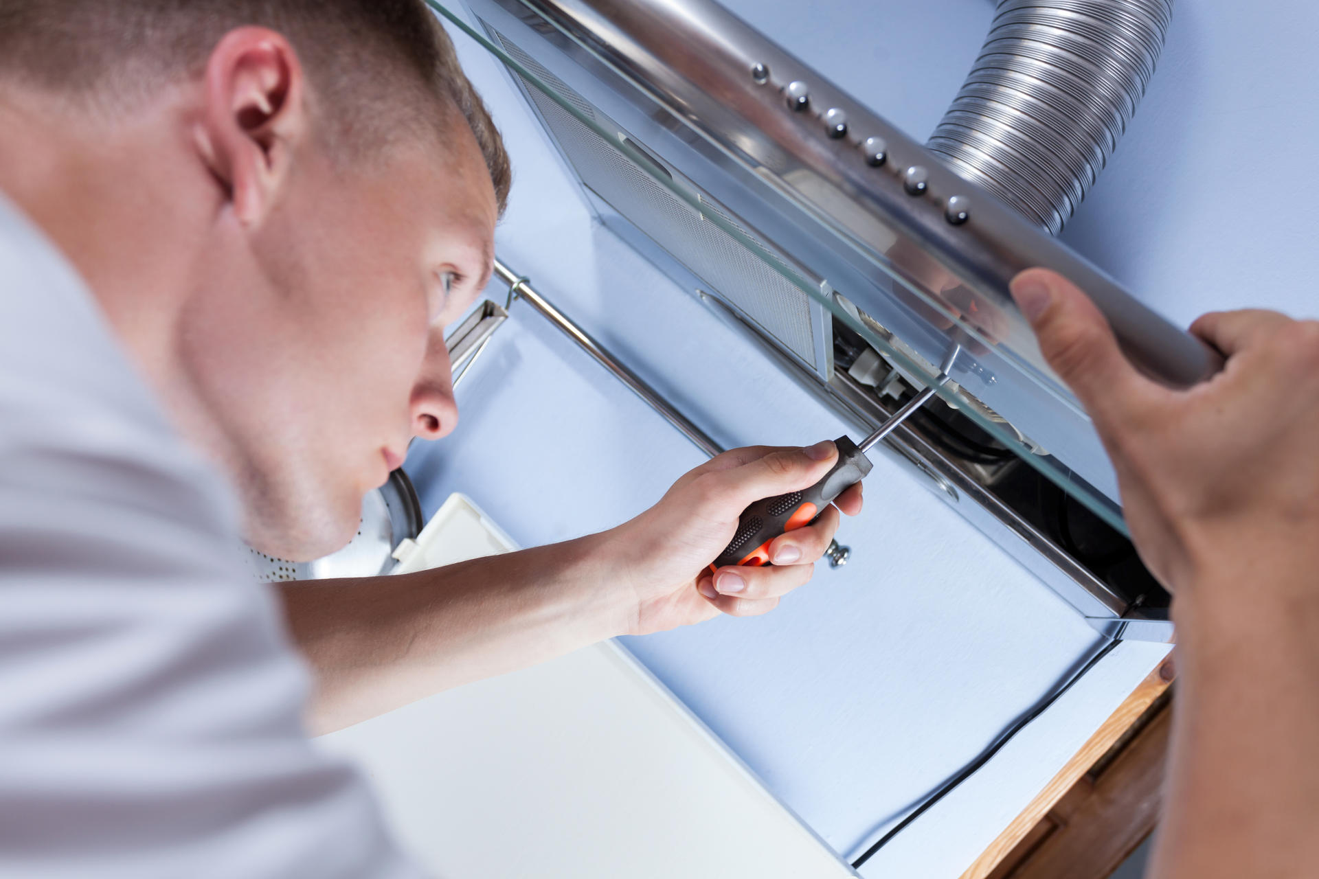 Photograph of a tradesman fixing an extractor fan with tools