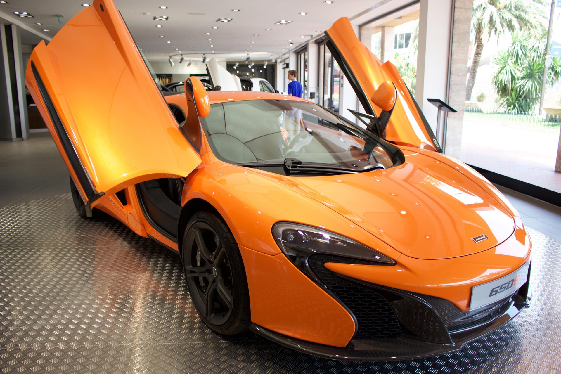 Photograph of an orange McLaren sports car in a showroom