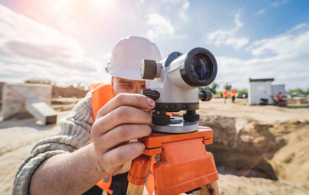 Photograph of a man in a hard hat using surveying equipment