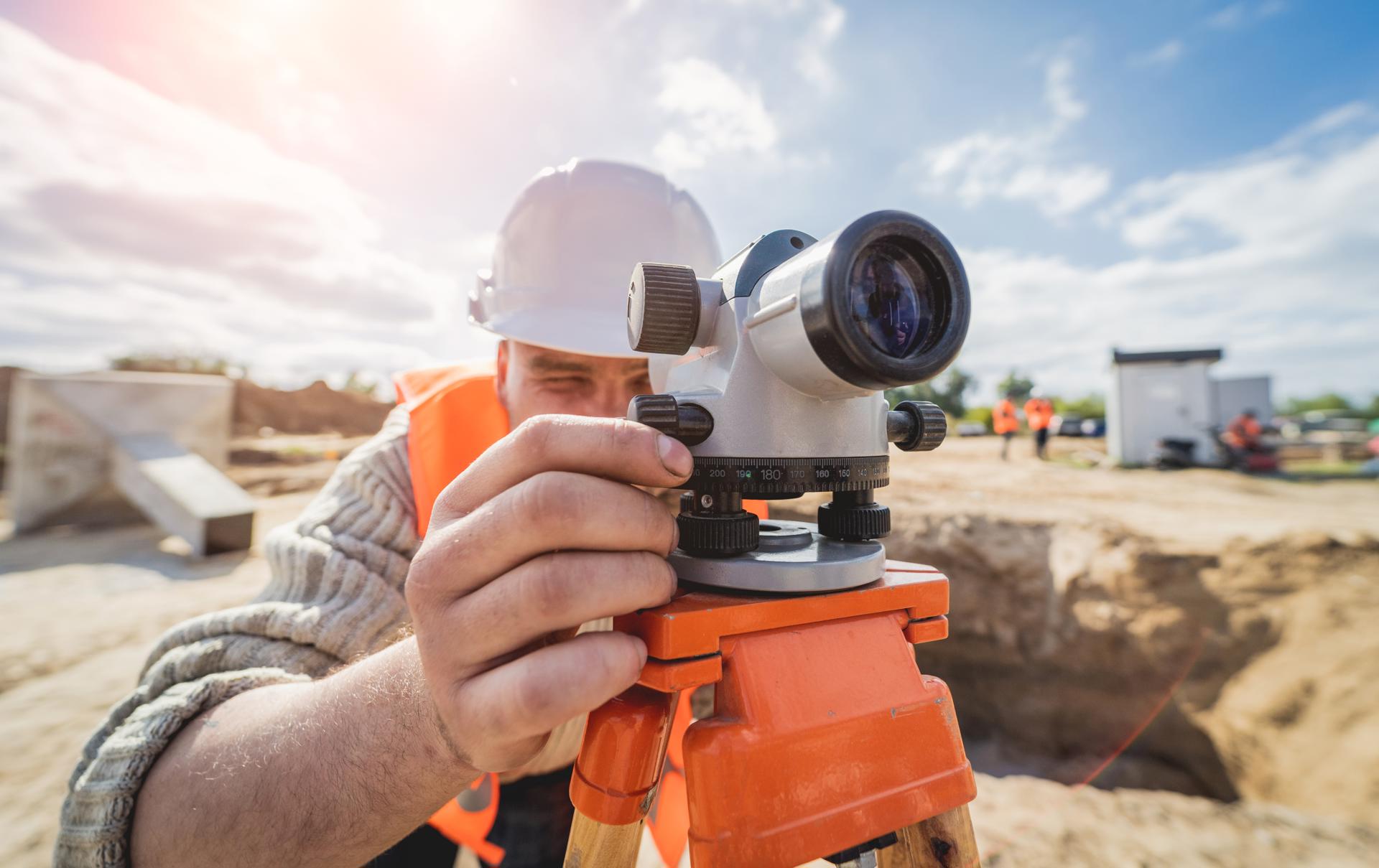 Photograph of a man in a hard hat using surveying equipment